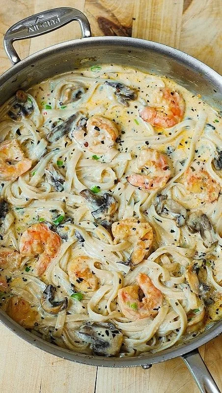 Creamy shrimp and mushroom pasta dish garnished with herbs