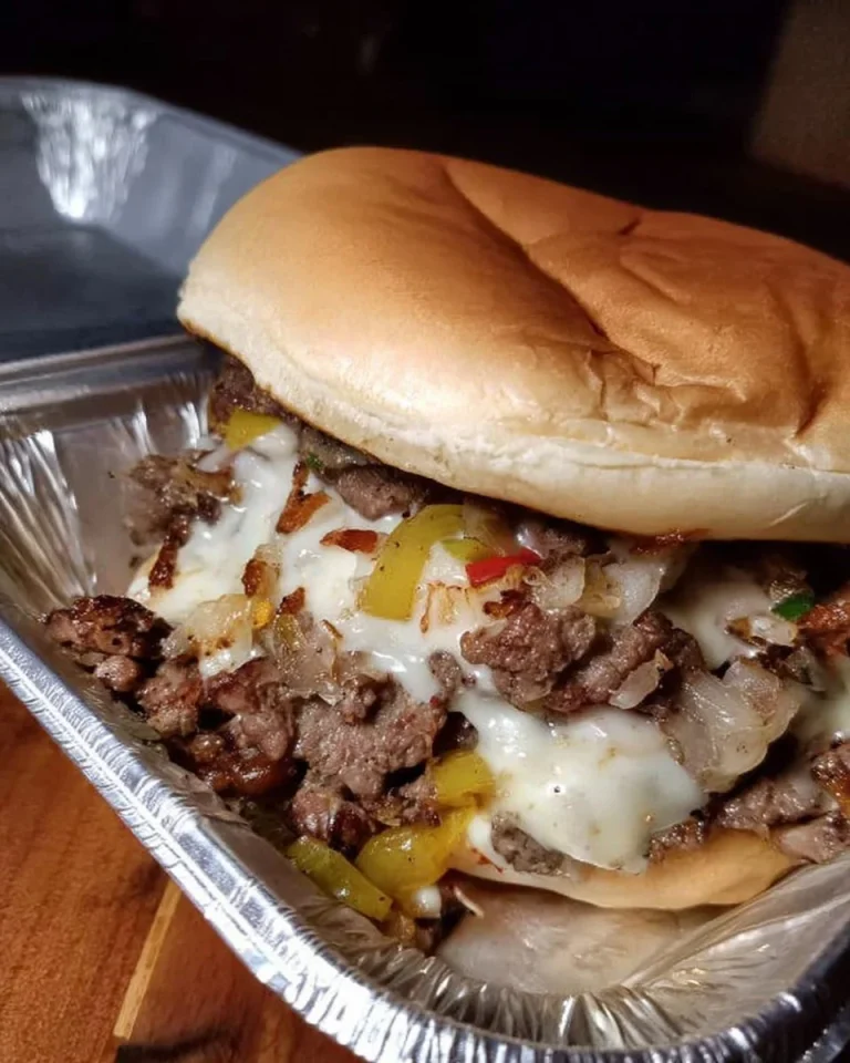 Philly Cheesesteak Cheeseburger with melted cheese and grilled onions on a bun.