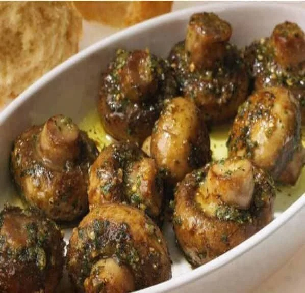 Plate of roasted garlic mushrooms garnished with herbs.