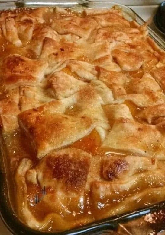 Delicious Triple-Crust Peach Cobbler fresh out of the oven, served in a rustic dish.
